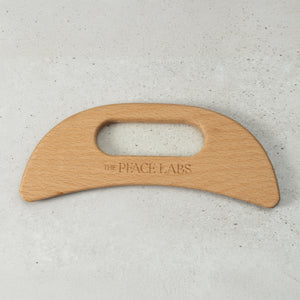 Wooden tool with 'The Peace Labs' branding on a light gray background